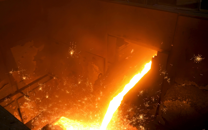 Electric arc furnace melting steel at high temperature